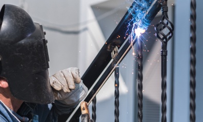 A worker welding metal handrails on the stairs roy ut