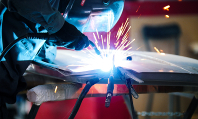 Welding industrial worker in helmet repair detail in car service roy ut